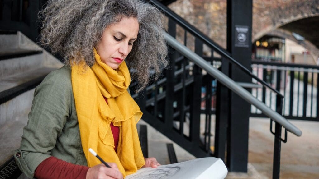 Woman sitting on a staircase with skecth pad and pencil